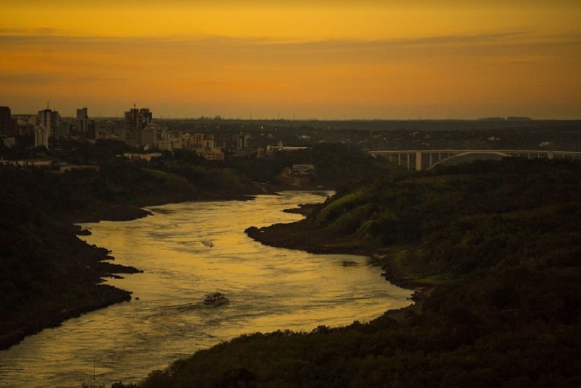 Fim de tarde na fronteira entre Brasil e Paraguai, com destaque para o Rio Paraná, para os prédios de Ciudad del Este e para a Ponte da Amizade. Imagem: Marcos Labanca/H2FOZ