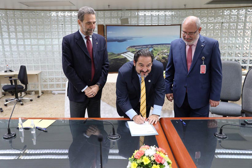Secretário-executivo da Olade assina o documento, acompanhado pelos dois diretores-gerais de Itaipu. Foto: Abel Rojas/Itaipu Binacional (Paraguai)